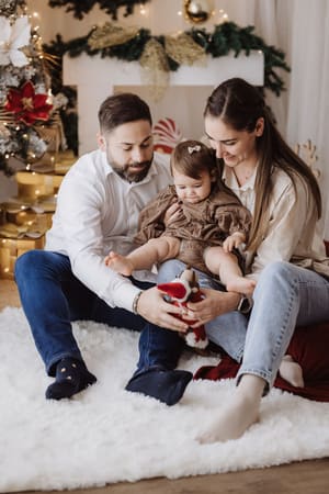 Famiglia seduta sul tappeto bianco davanti al camino decorato