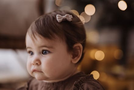 Profilo di una bambina con un fiocco tra i capelli e luci dorate sullo sfondo